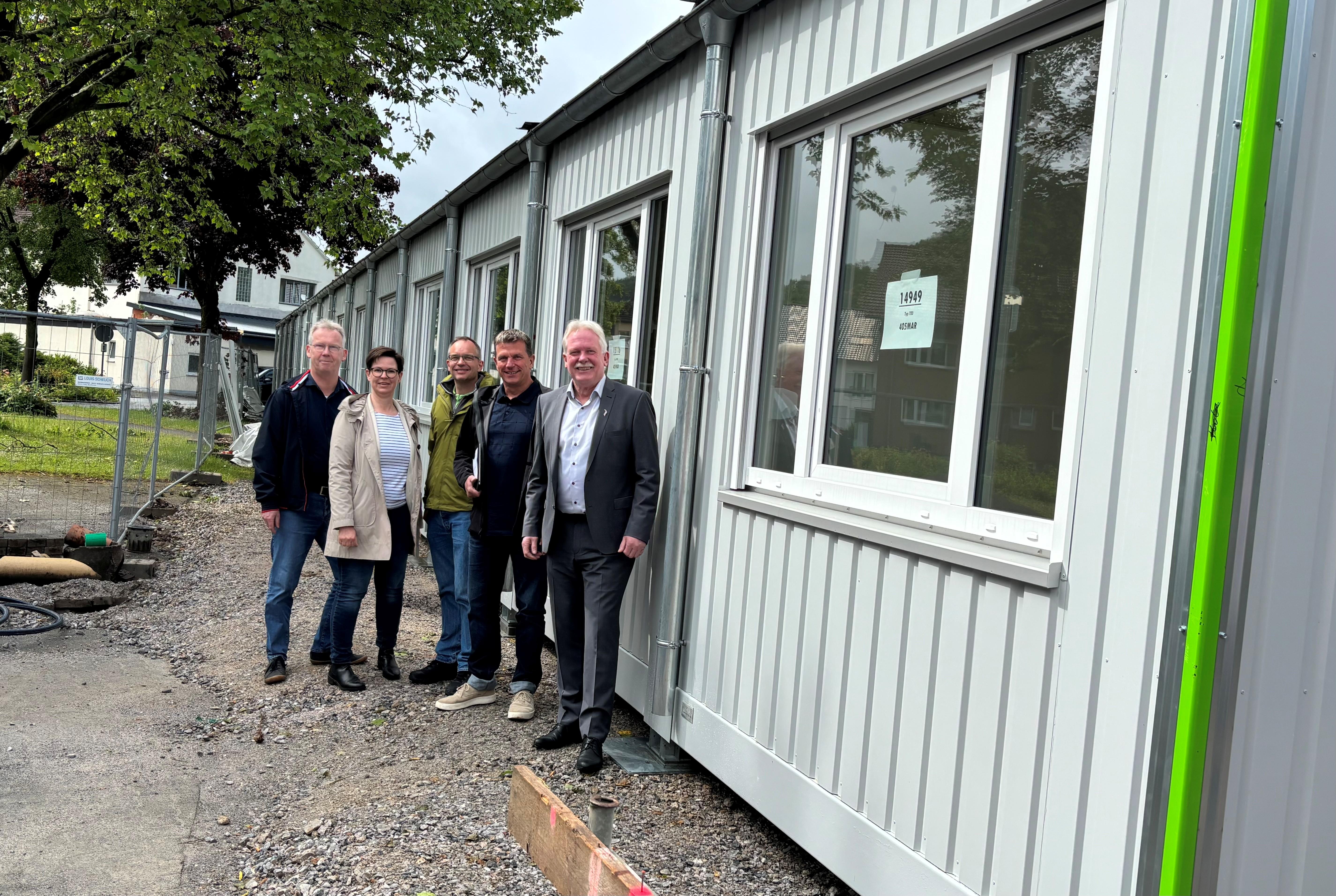 (Gruppenfoto) Zufriedene Gesichter bei allen Beteiligten: Ralf Trachternach (kommissarischer Schulleiter des Carolus-Magnus-Gymnasiums), Nadin Quest (Leiterin des Schulverwaltungsamts), Thomas Daake (Leiter des Hoch- und Tiefbauamts), Architekt Jürgen Kepplin und Bürgermeister Thomas Schröder (v.l.) freuen sich über die ersten Container an der Schöffenwiese.