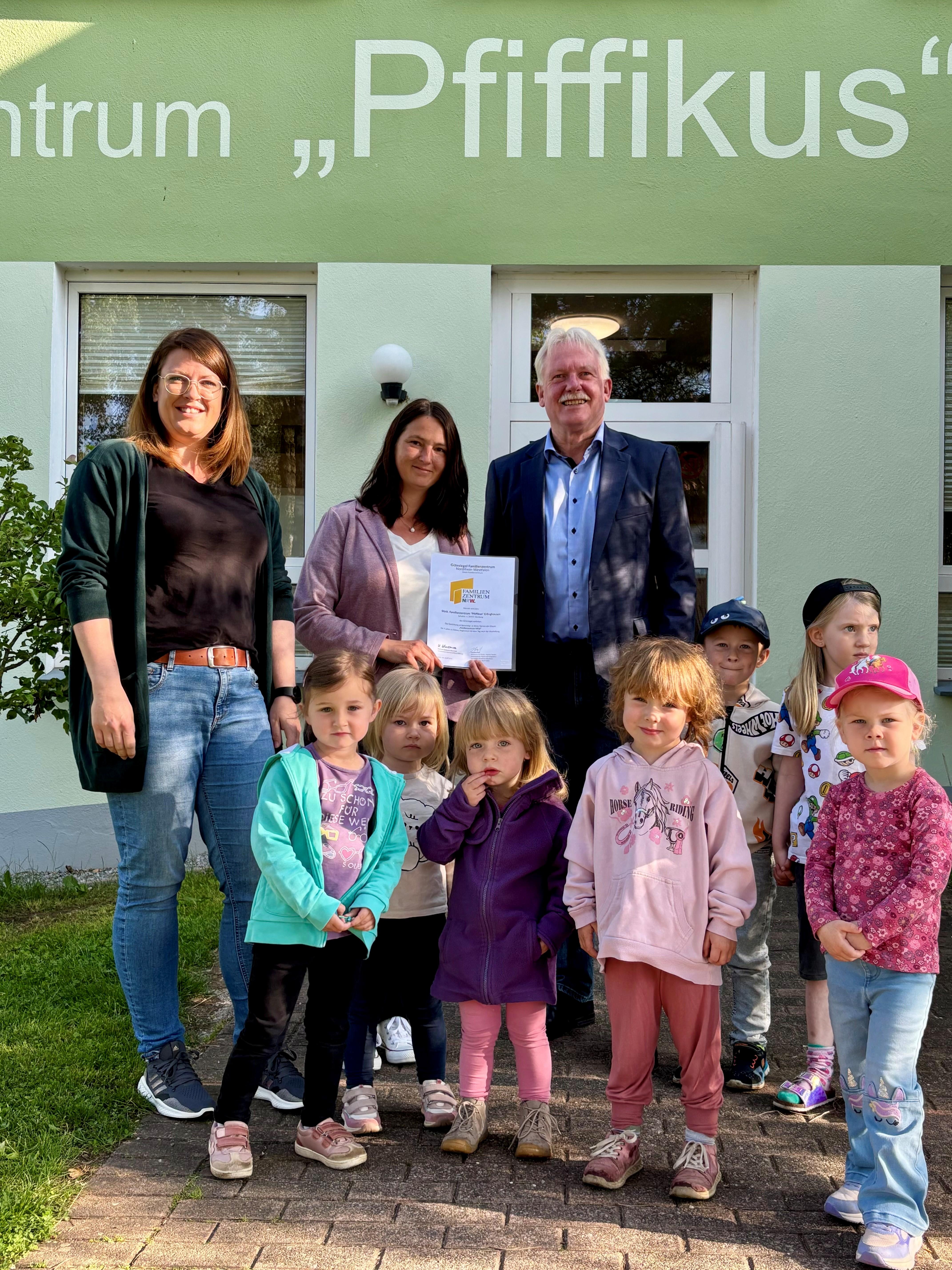 Die stellvertretende Leiterin Nadja Otto, Leiterin Melina Prior und Bürgermeister Thomas Schröder freuen sich mit den Kindern des Familienzentrums Pfiffikus in Erlinghausen über die erfolgreiche Rezertifizierung.