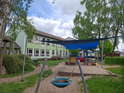 Das Foto zeigt den Spielplatz und das Gebäude des Kindergartens "Pfiffikus".